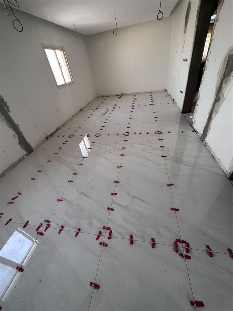 ריצוף באריחי שיש לבנים גדולים בחדר, בזמן ההתקנה