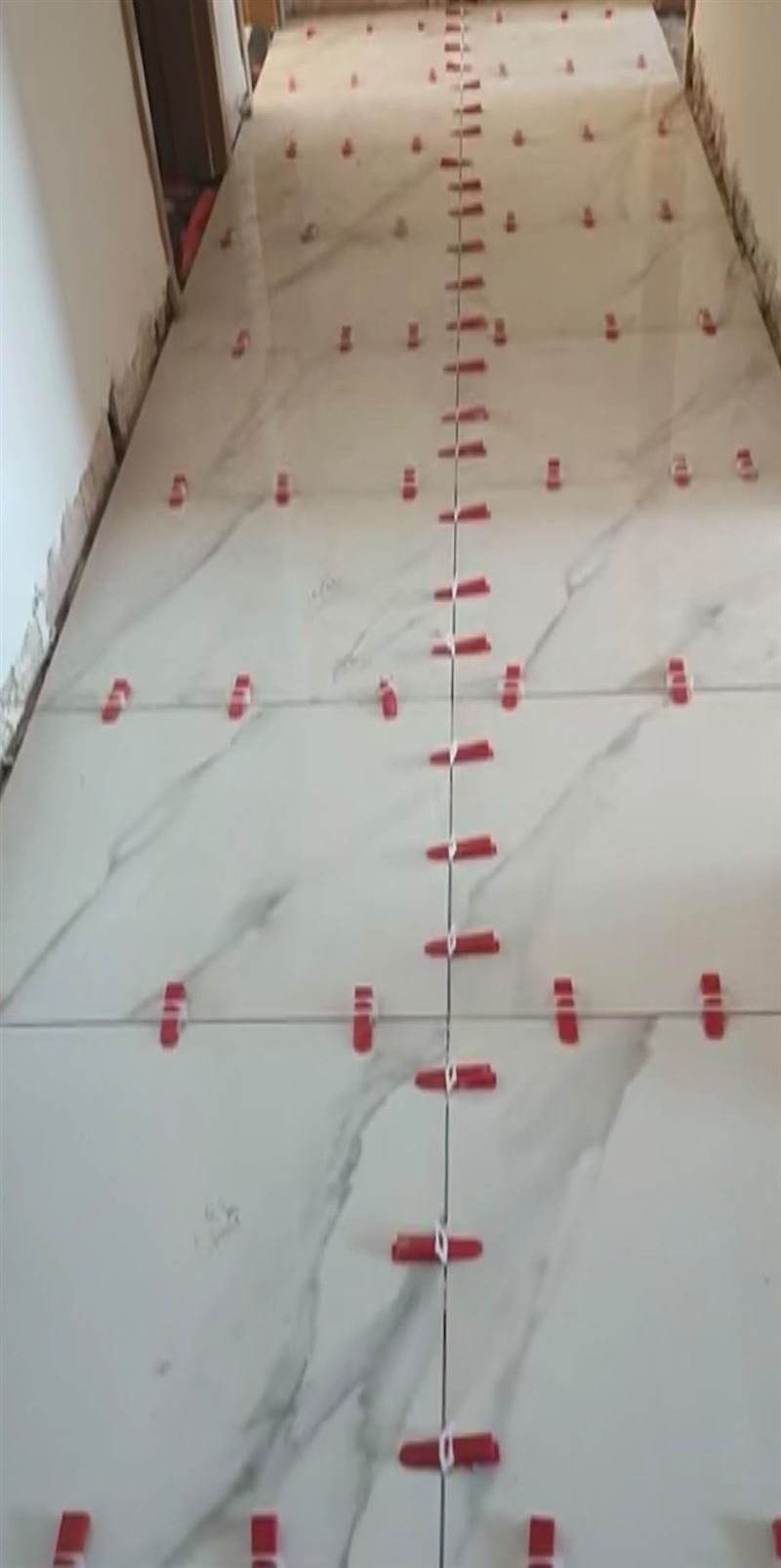 ריצוף מסדרון באריחי שיש לבנים, עם פלסי יישור אדומים