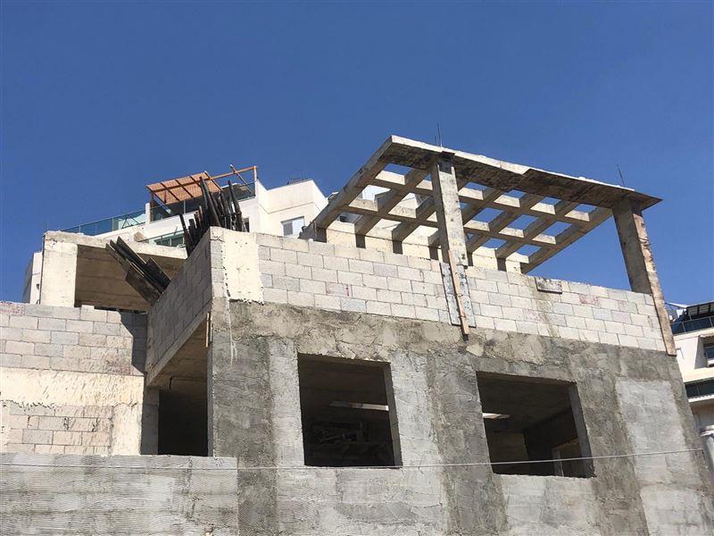 שלד בטון ובלוקים של בניין, עם פרגולה יצוקה על הגג